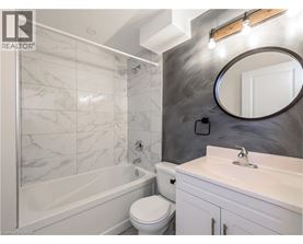 A bathroom with a marble tile shower, white toilet, and sink.