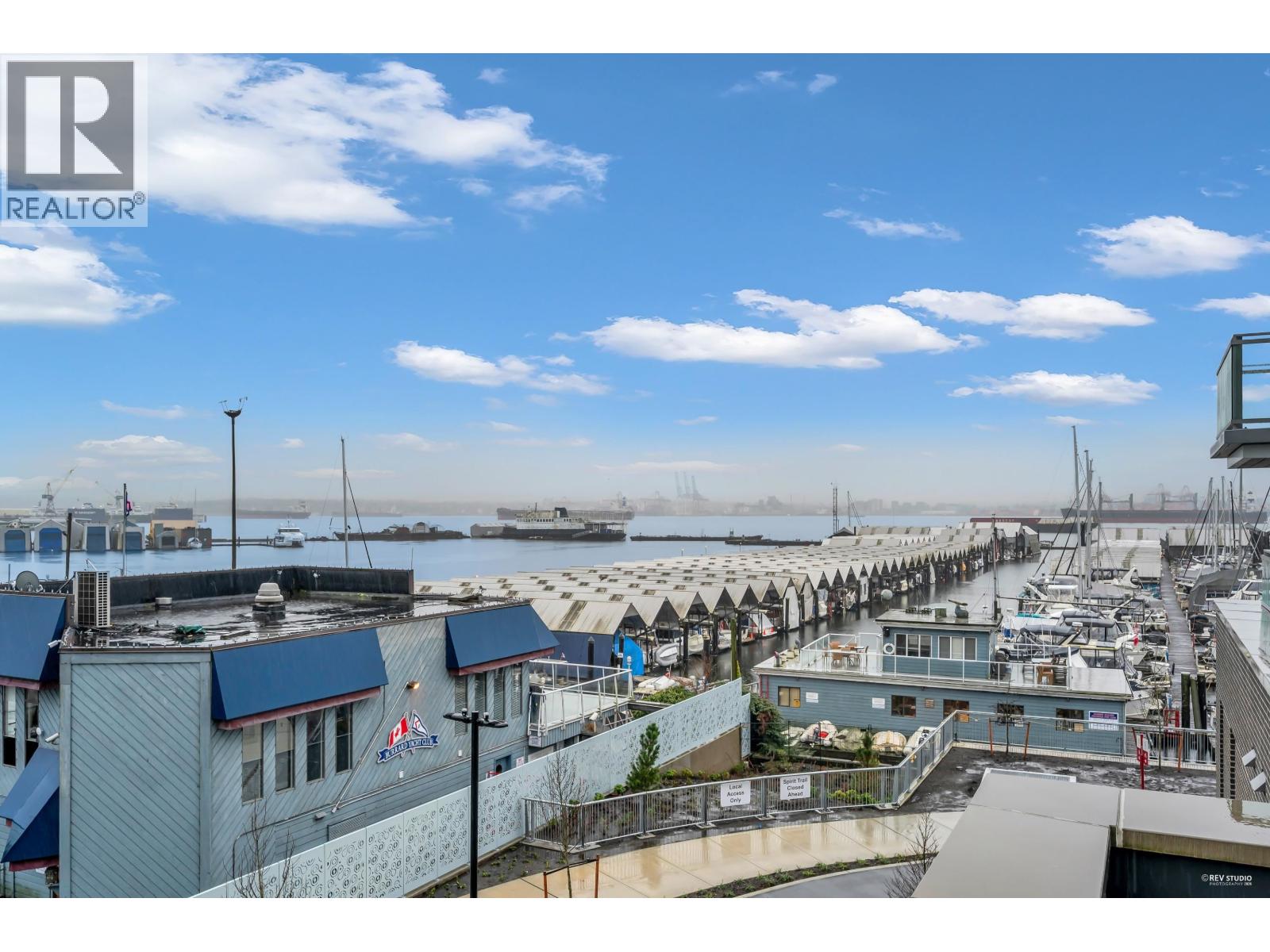 A marina with boats and buildings under a blue sky.