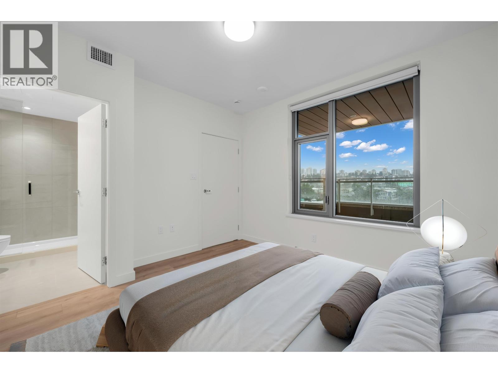 A bedroom with a large bed and a window overlooking a field.
