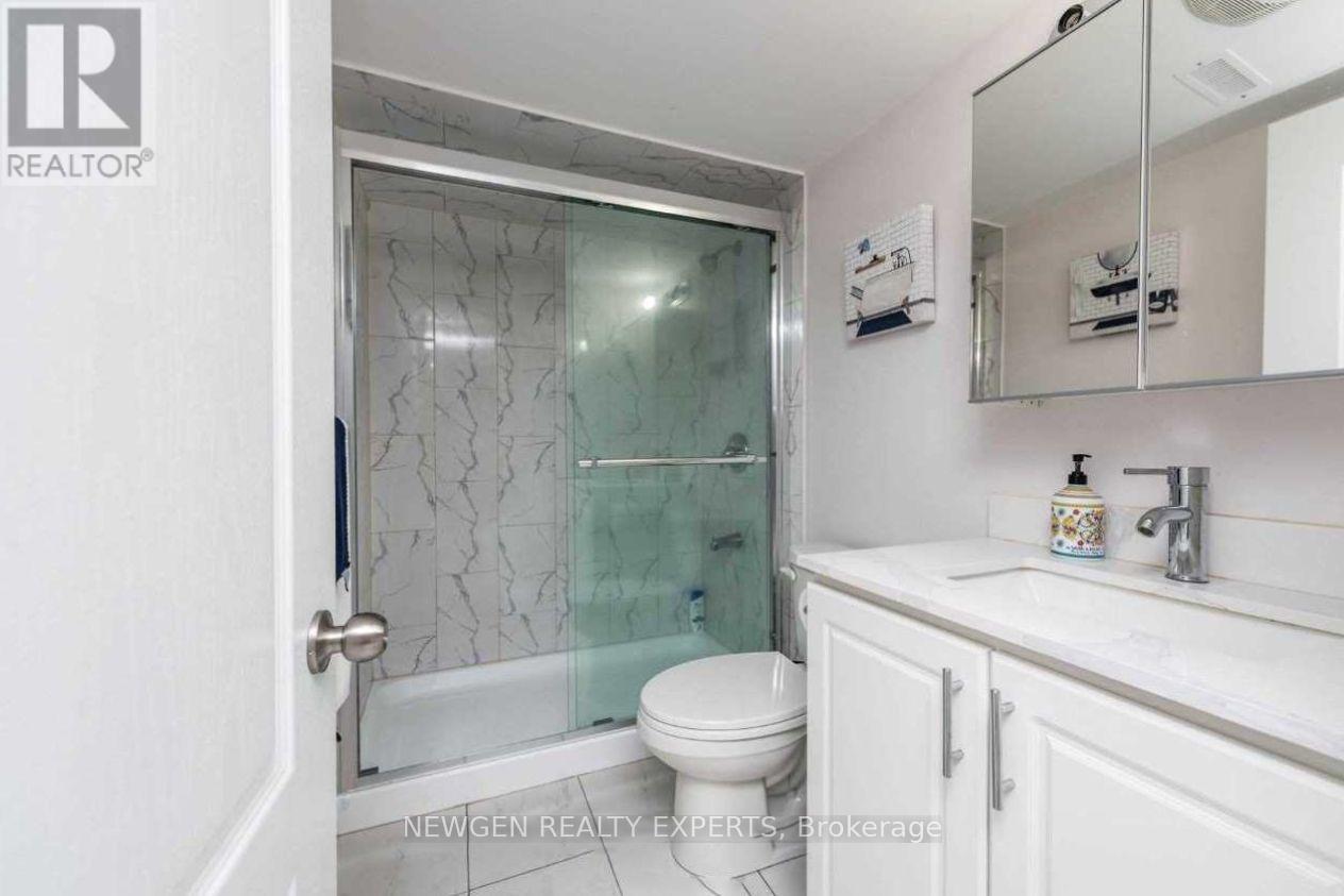 A bathroom with a glass shower door and a toilet.