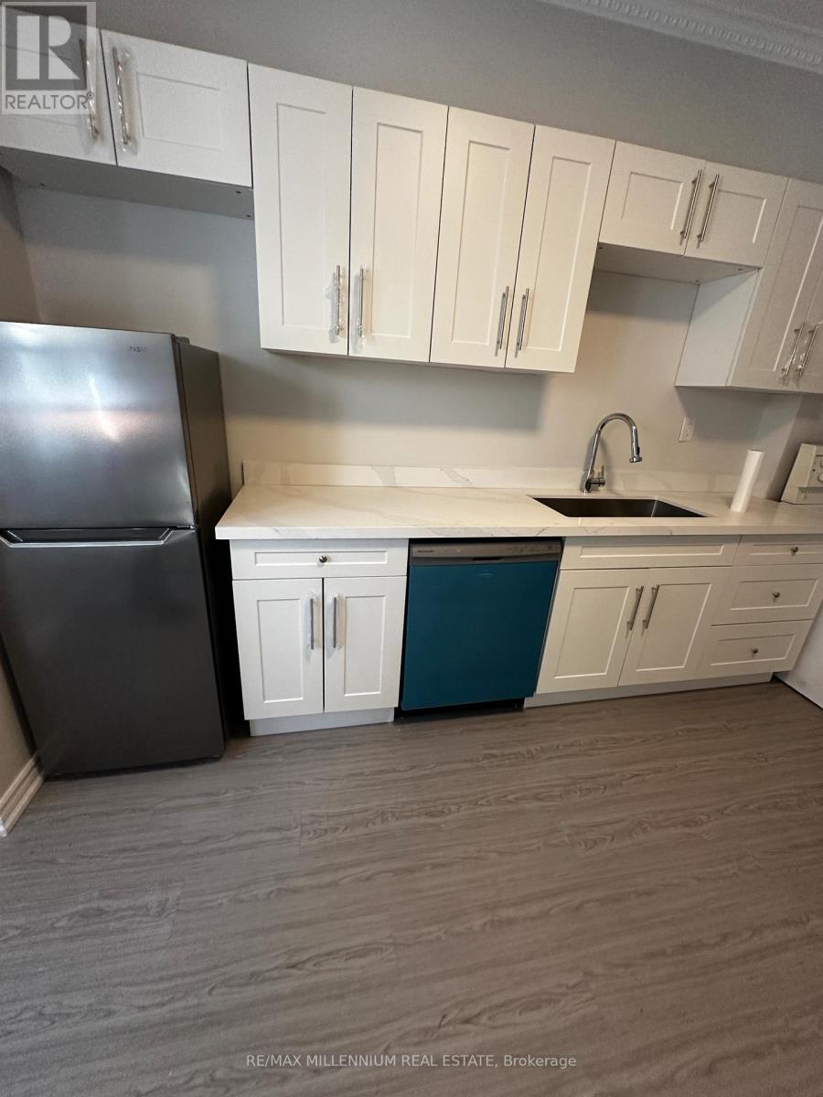 A kitchen with a black refrigerator, white cabinets, and a blue island.