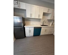 A kitchen with a black refrigerator, white cabinets, and a blue island.