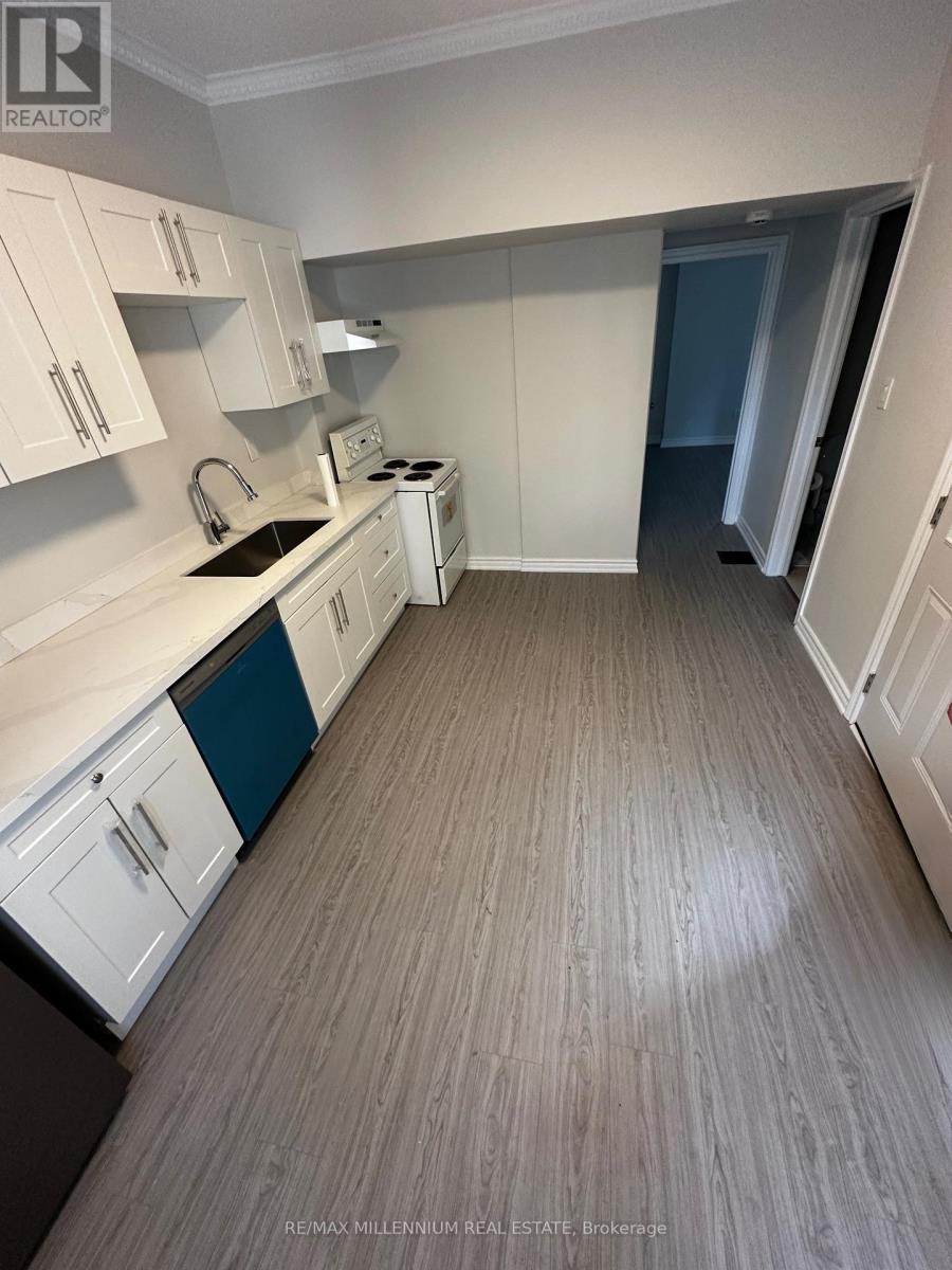 A kitchen with white cabinets and a wooden floor.