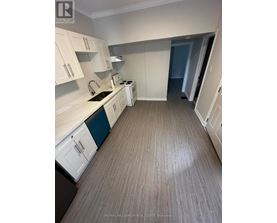 A kitchen with white cabinets and a wooden floor.