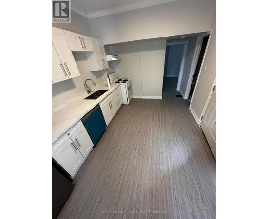 A kitchen with white cabinets and a wooden floor.