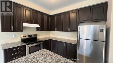 A kitchen with dark brown cabinets and a granite countertop.
