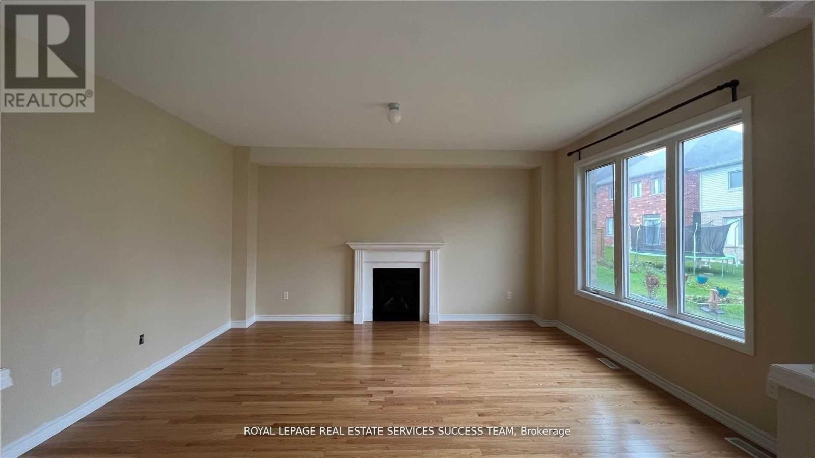 A spacious room with wooden floors and a fireplace.