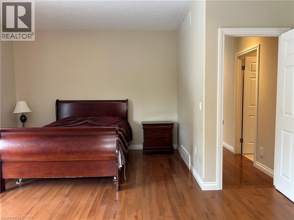 A bedroom with a bed, nightstand, and wooden floors.