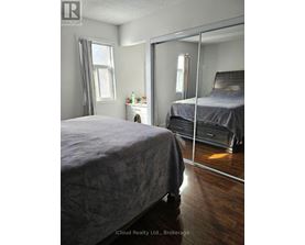 A bedroom with a large bed and a mirrored closet door.