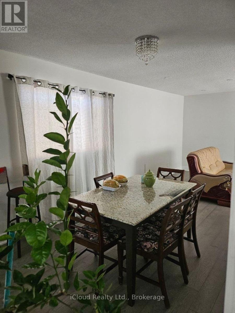 A dining room with a table set for two and a plant in the foreground.