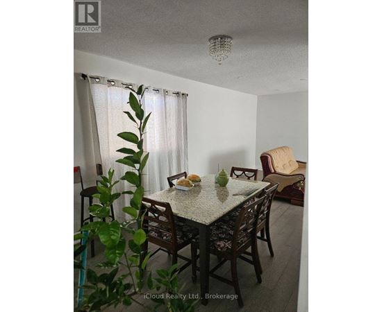 A dining room with a table set for two and a plant in the foreground.