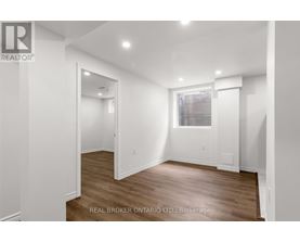 A white room with wood flooring and a window with blinds.