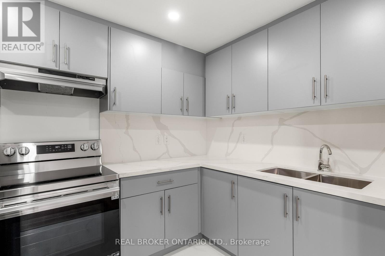 A modern kitchen with grey cabinets and a stainless steel oven.