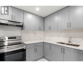 A modern kitchen with grey cabinets and a stainless steel oven.