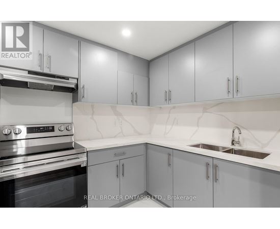 A modern kitchen with grey cabinets and a stainless steel oven.