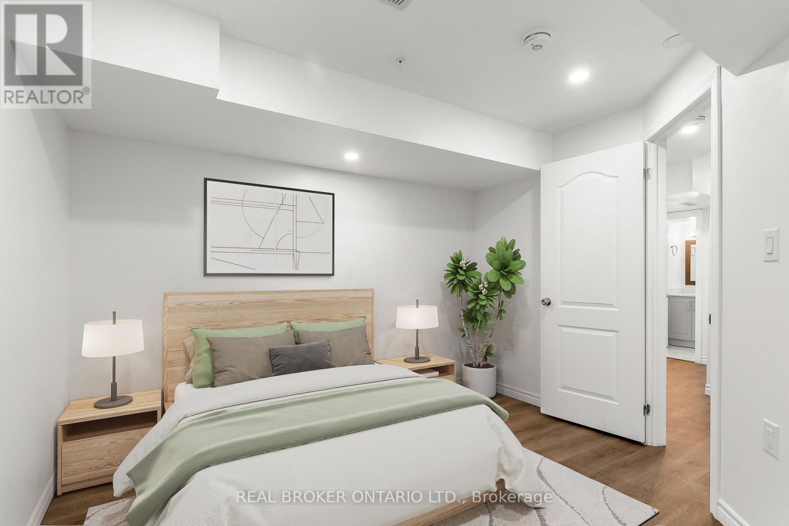 A bedroom with a bed, nightstands, and a plant.