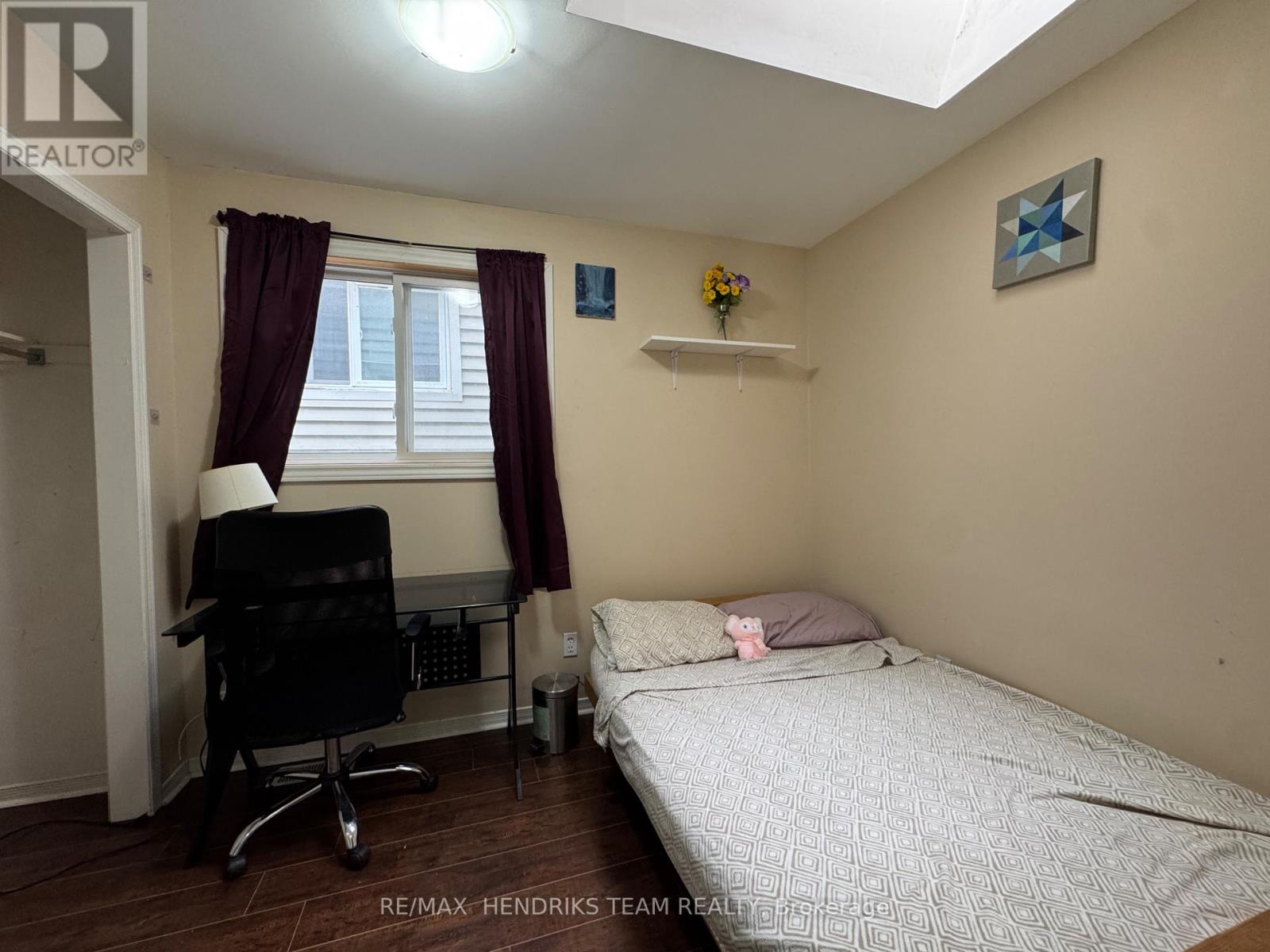 A bedroom with a bed, desk, and window.