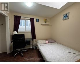 A bedroom with a bed, desk, and window.