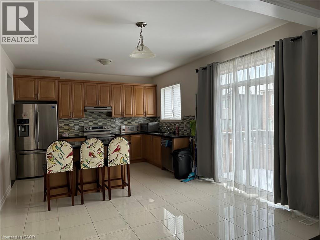 A kitchen with a refrigerator, sink, and two chairs.