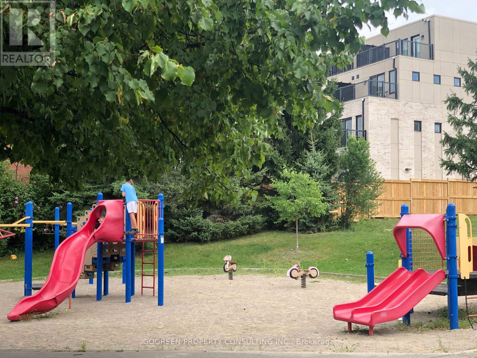 A playground with a red slide and a child playing on it.