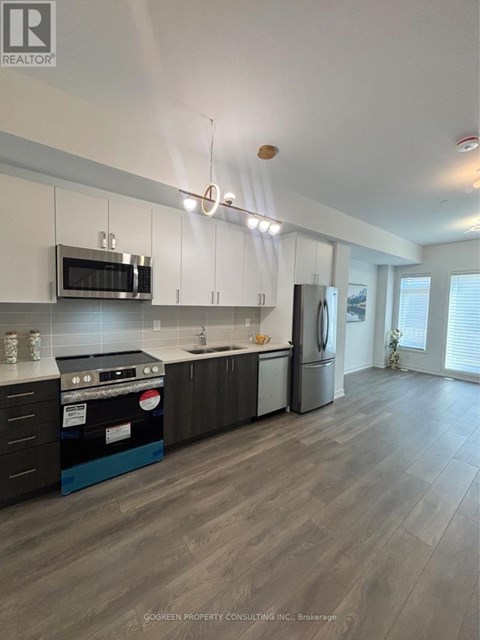 A modern kitchen with dark wood floors and white walls.