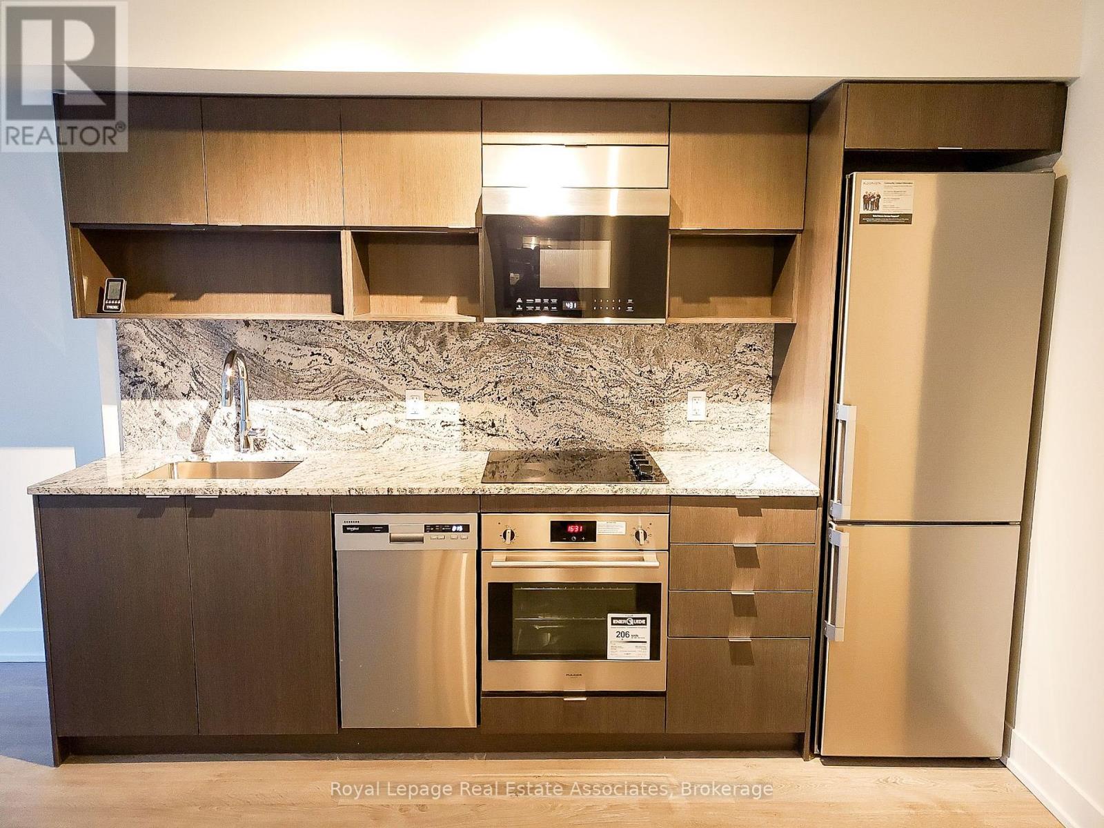A modern kitchen with a marble countertop and stainless steel appliances.