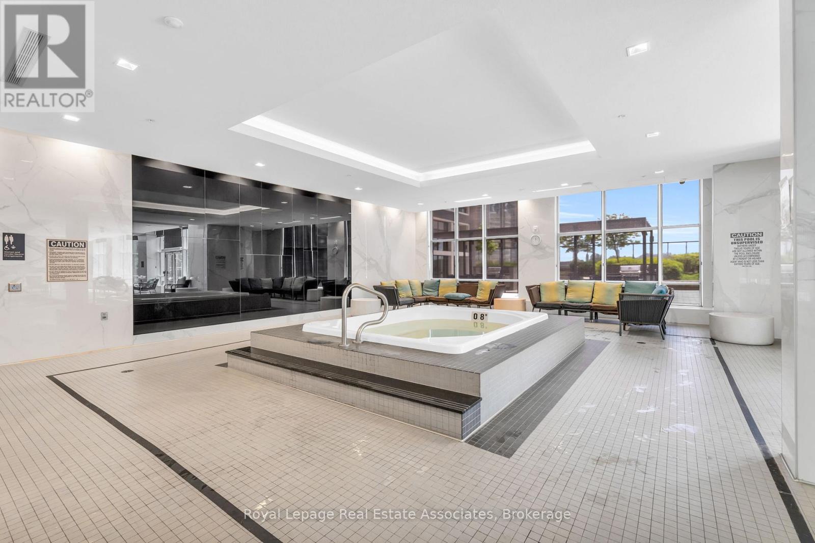 A large, modern indoor swimming pool area with a hot tub and seating area.