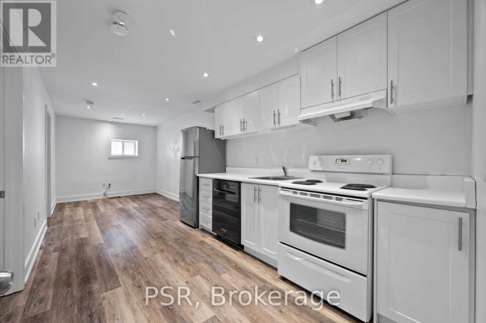 A modern kitchen with white appliances and wooden floors.