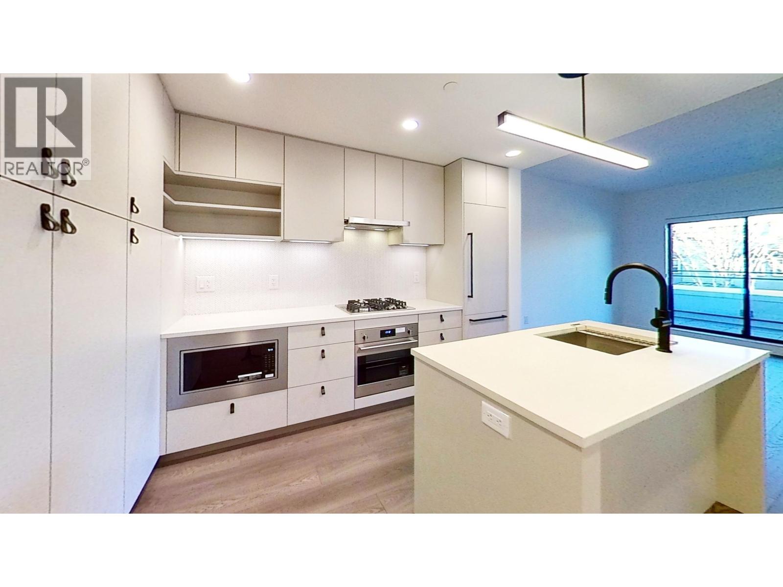 A modern kitchen with a white countertop and stainless steel appliances.