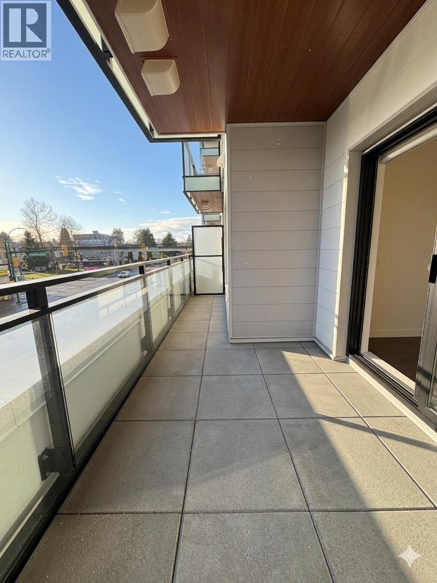 A balcony with a glass railing and a view of trees and a building in the distance.