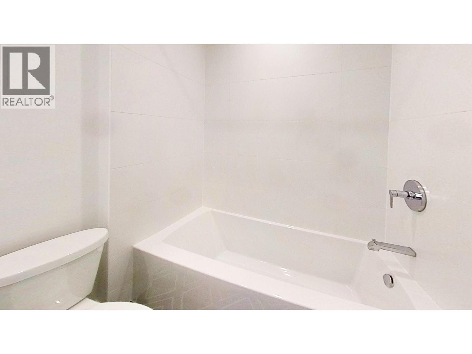 A white bathroom with a tub, toilet and sink.