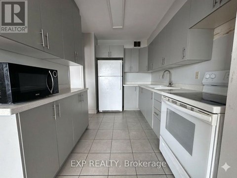 A kitchen with white appliances and grey cabinets.