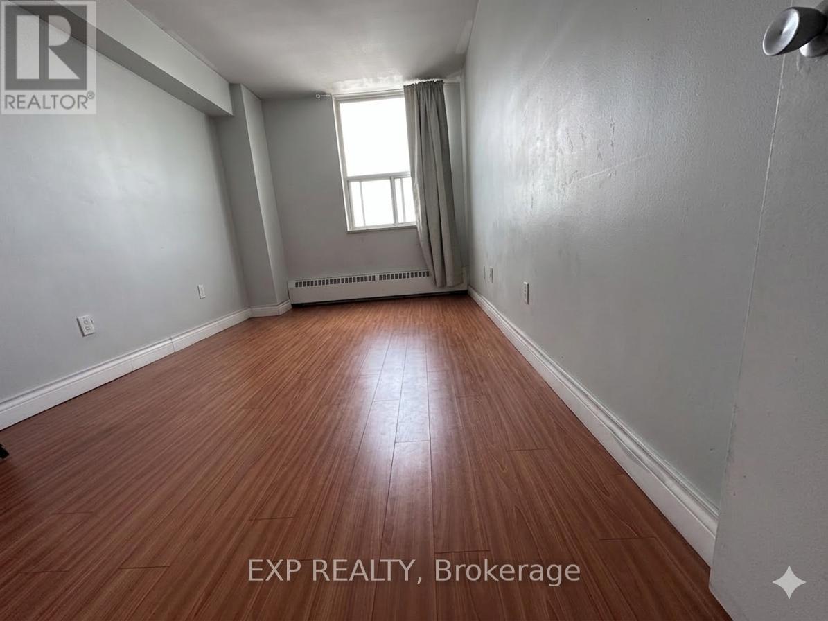 A room with wooden flooring and a window with curtains.