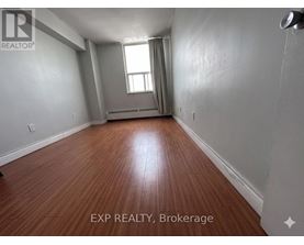 A room with wooden flooring and a window with curtains.