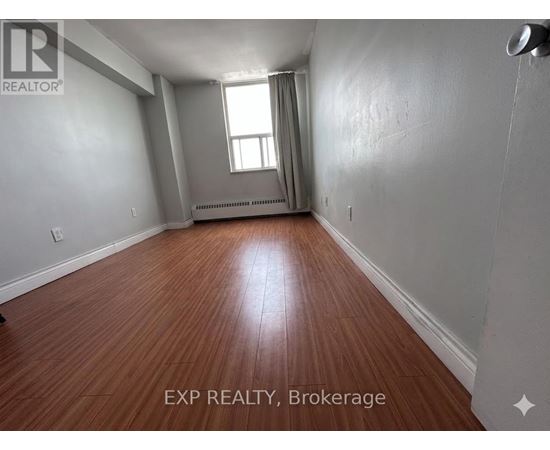 A room with wooden flooring and a window with curtains.