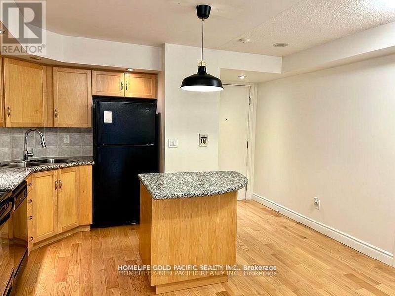 A kitchen with wooden cabinets and a black fridge.