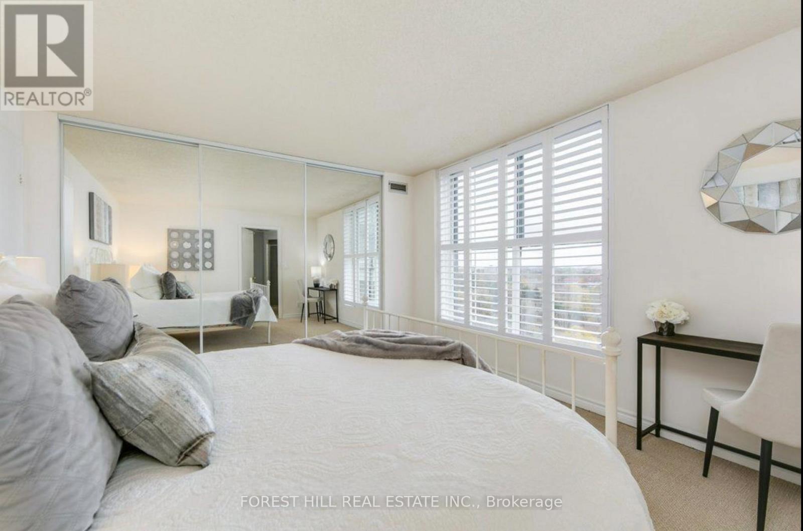 A bedroom with a large bed, a desk, and a mirror on the wall.