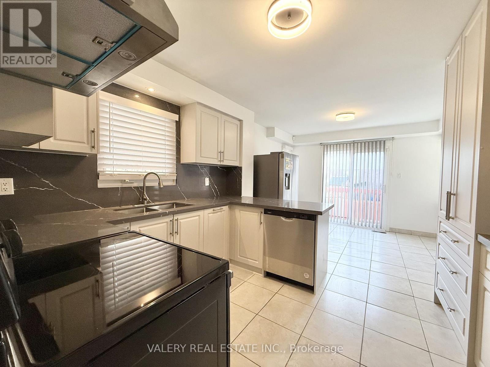 A kitchen with a black countertop and stainless steel appliances.