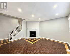 A living room with a fireplace and a staircase.
