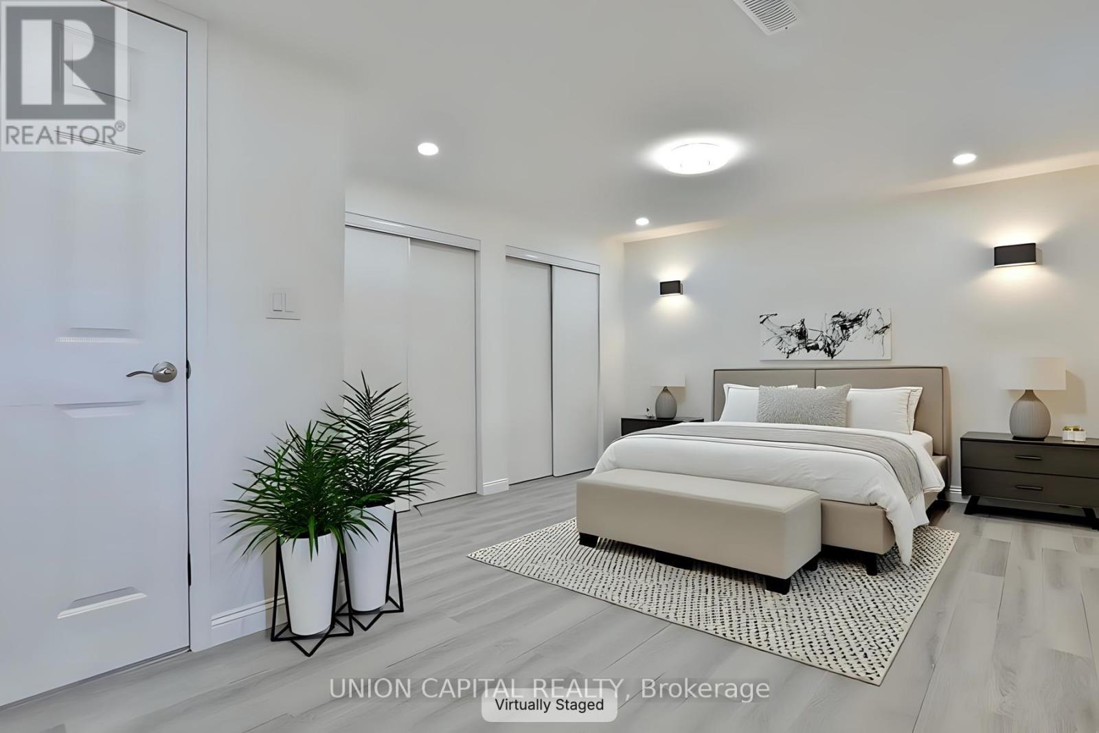 A bedroom with a large bed and a plant in a vase.