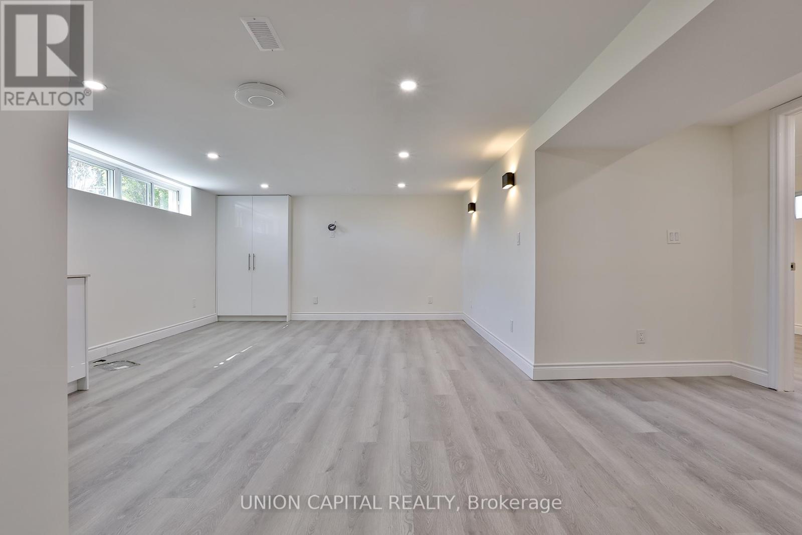 A spacious room with wood flooring and white walls, likely for sale.