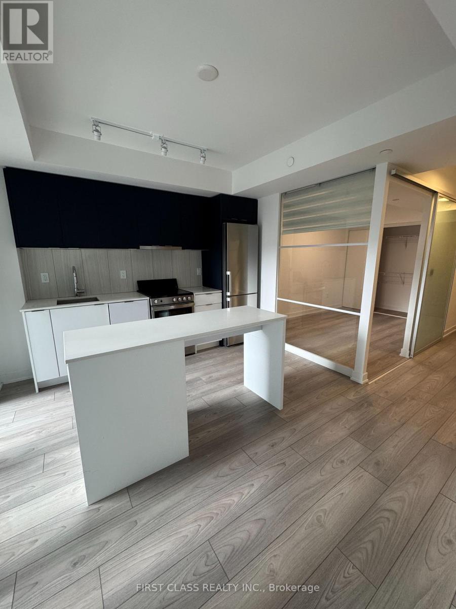 A modern kitchen with a white island and wooden flooring.