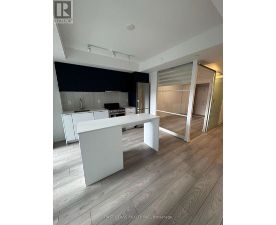 A modern kitchen with a white island and wooden flooring.
