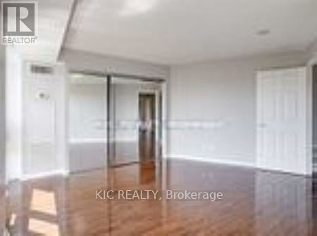 A room with a wooden floor and white walls, with a glass door leading to another room.