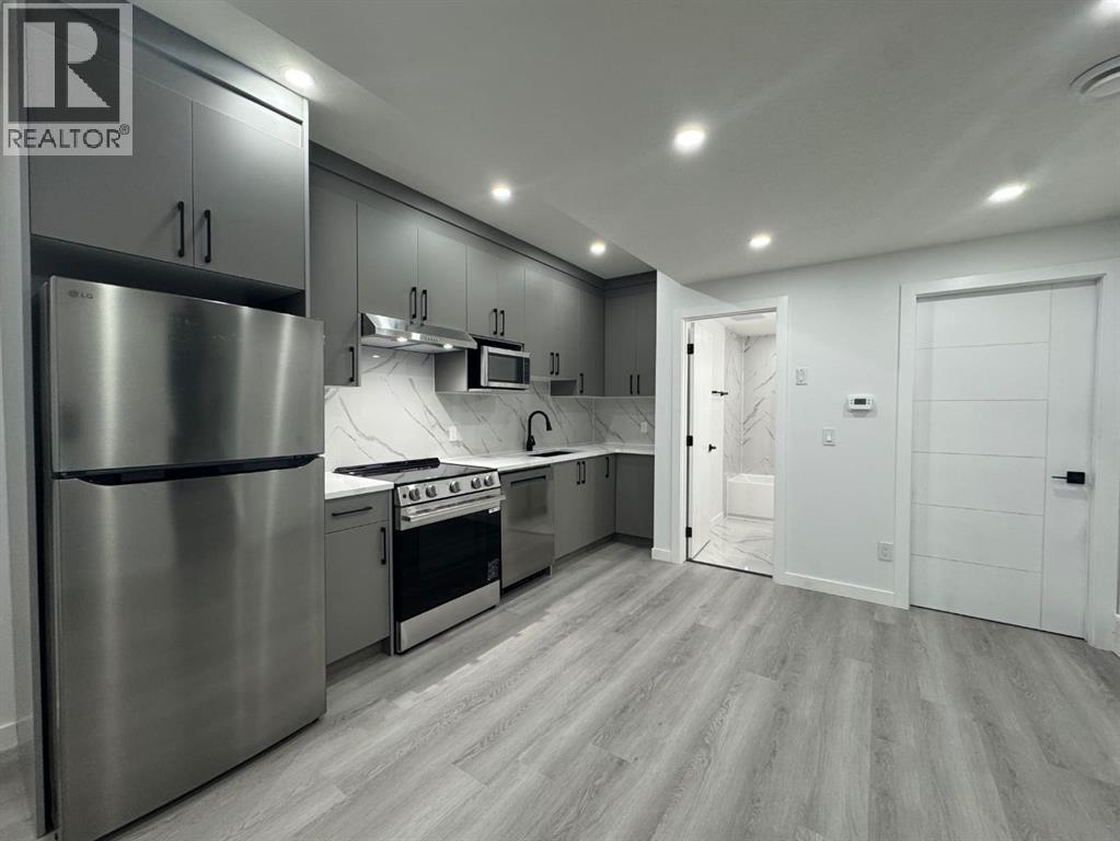A modern kitchen with a stainless steel refrigerator and wooden flooring.