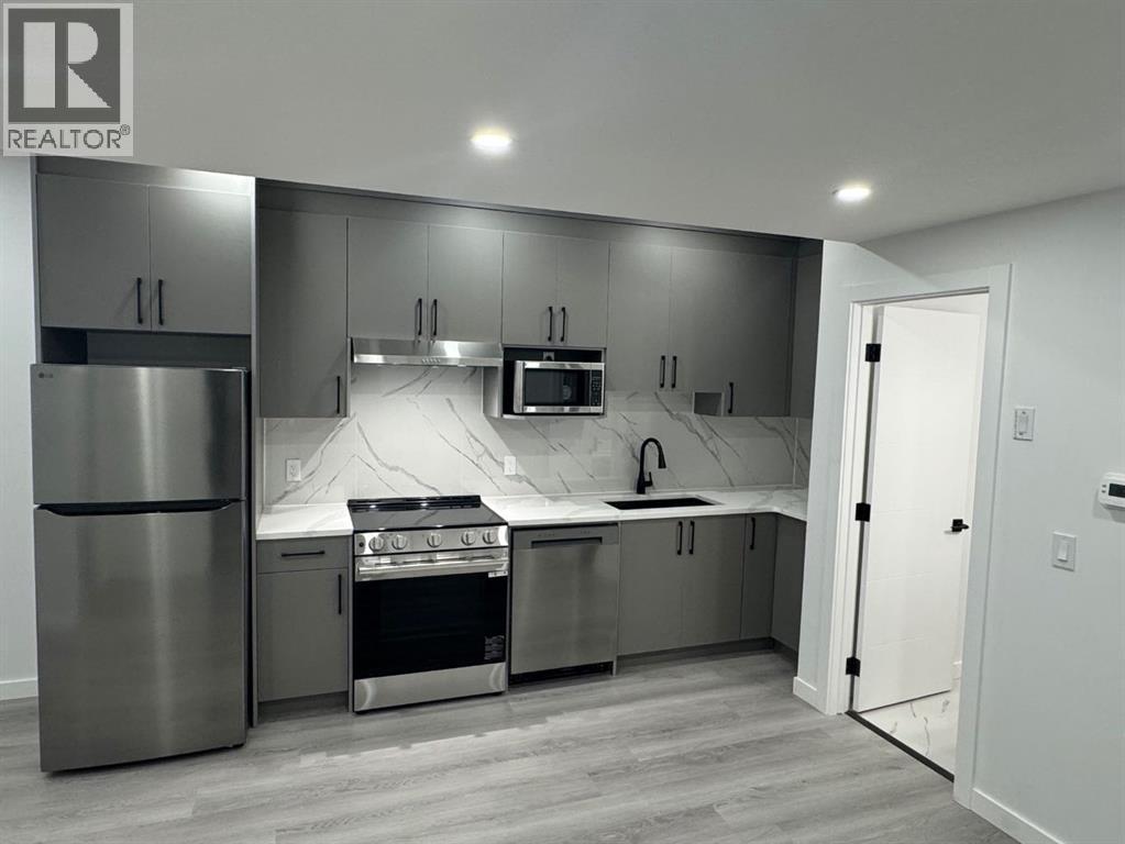 A modern kitchen with stainless steel appliances and a marble countertop.