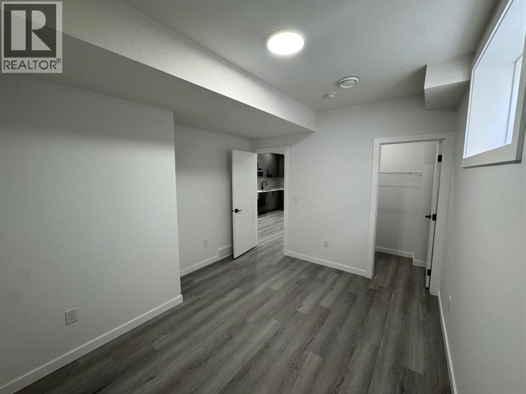A spacious room with wood flooring and white walls.