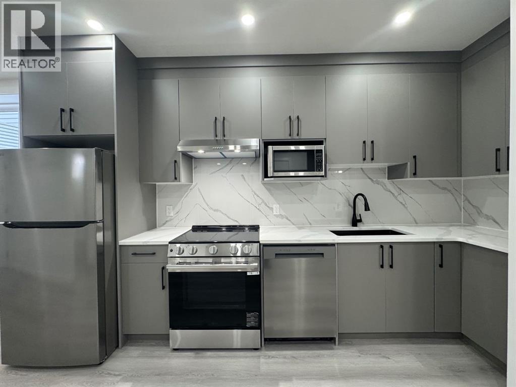 A modern kitchen with stainless steel appliances and a marble countertop.