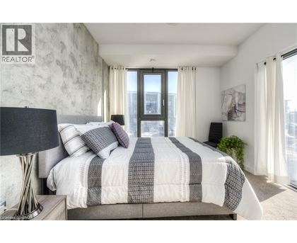 A bedroom with a large bed and a window overlooking a cityscape.