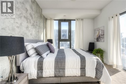 A bedroom with a large bed and a window overlooking a cityscape.